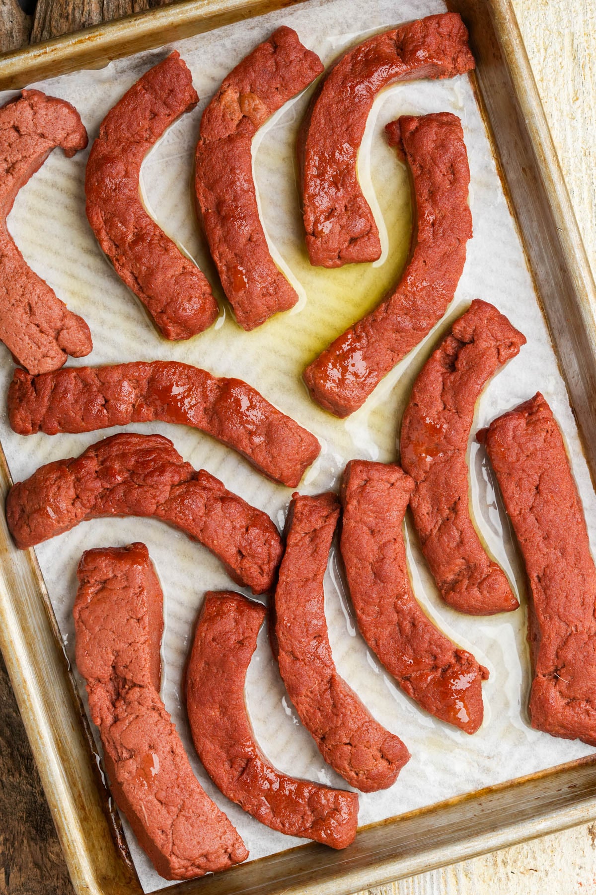 Seitan rib strips baked until firm on a parchment-lined baking pan.
