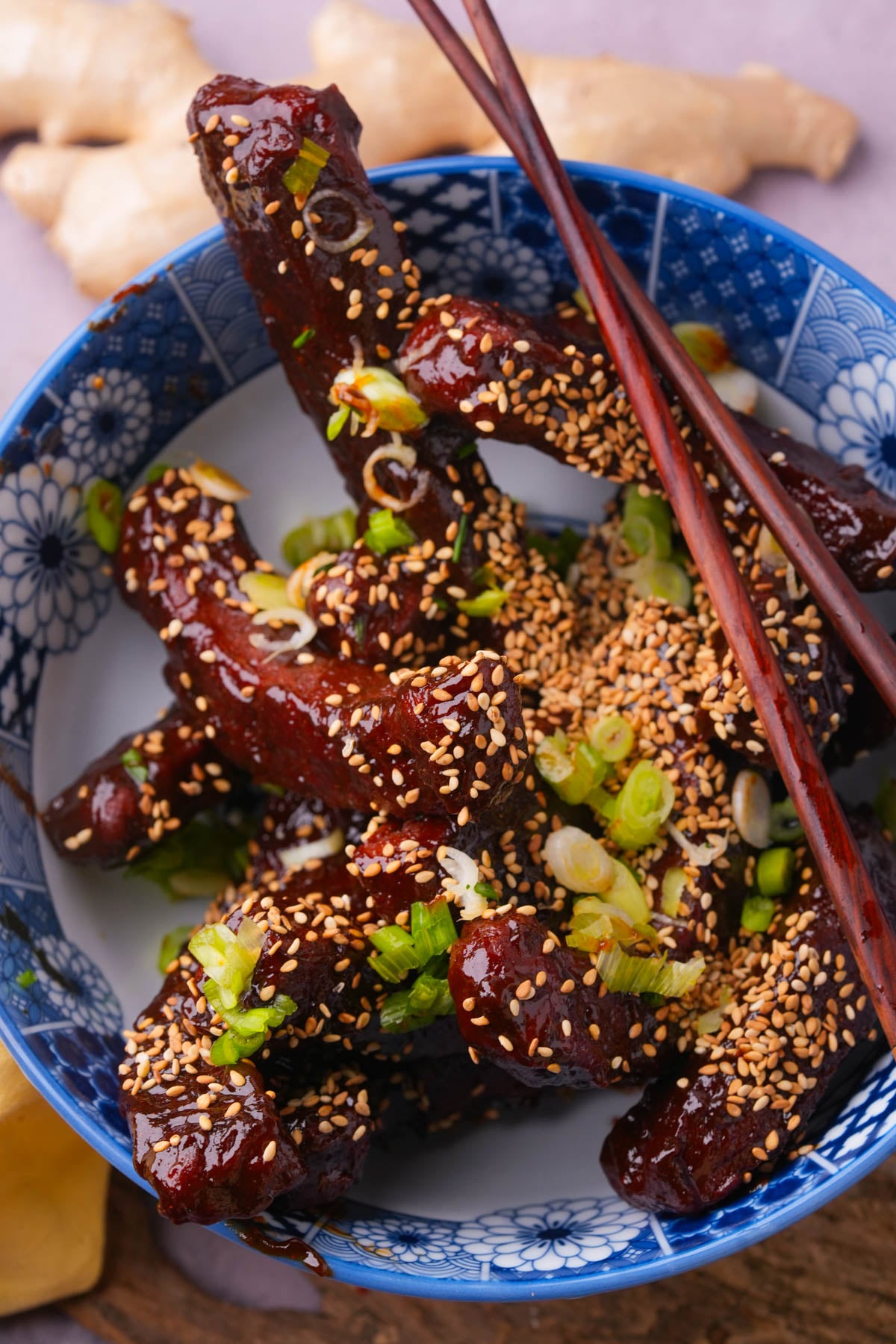 Vegan Chinese ribs plated in a blue bowl and garnished with toasted sesame seeds and scallions.