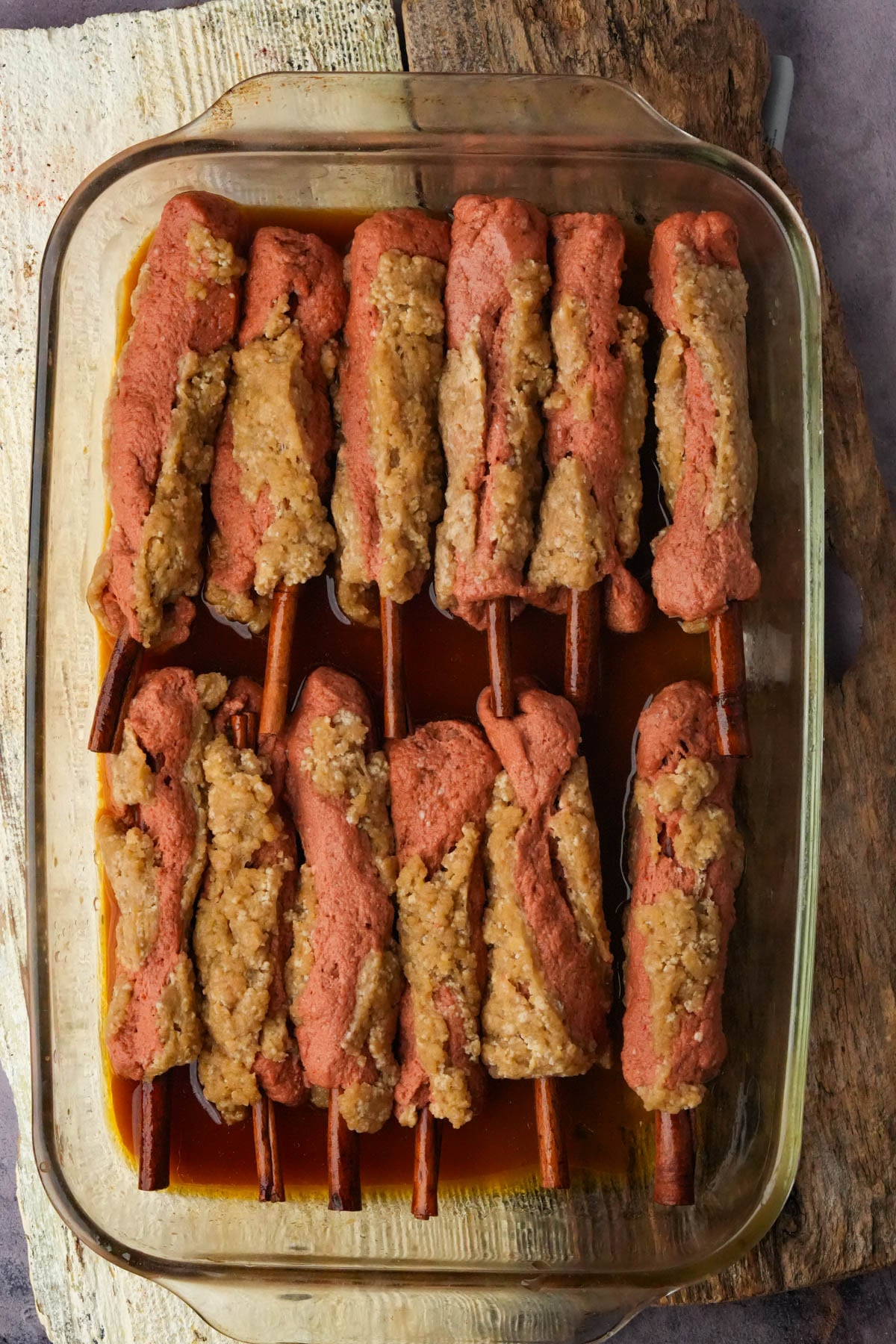 Vegan BBQ ribs lined up in a glass baking dish with stock and tamari, ready to roast.