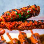 Vegan BBQ ribs glazed in sticky BBQ sauce with dark grill marks and minced chives.