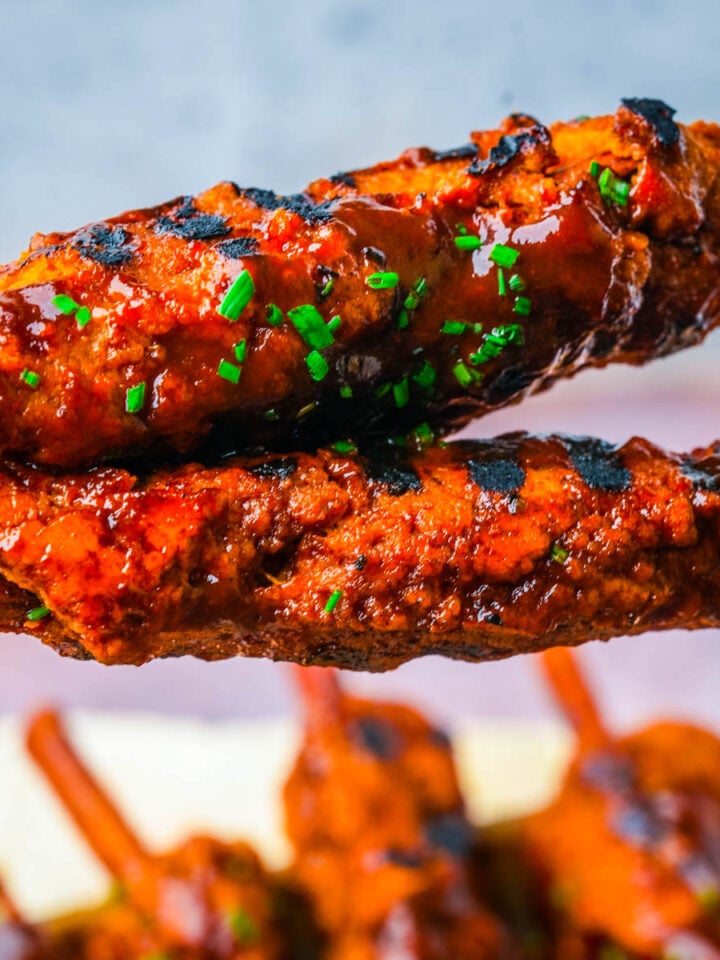 Vegan BBQ ribs glazed in sticky BBQ sauce with dark grill marks and minced chives.