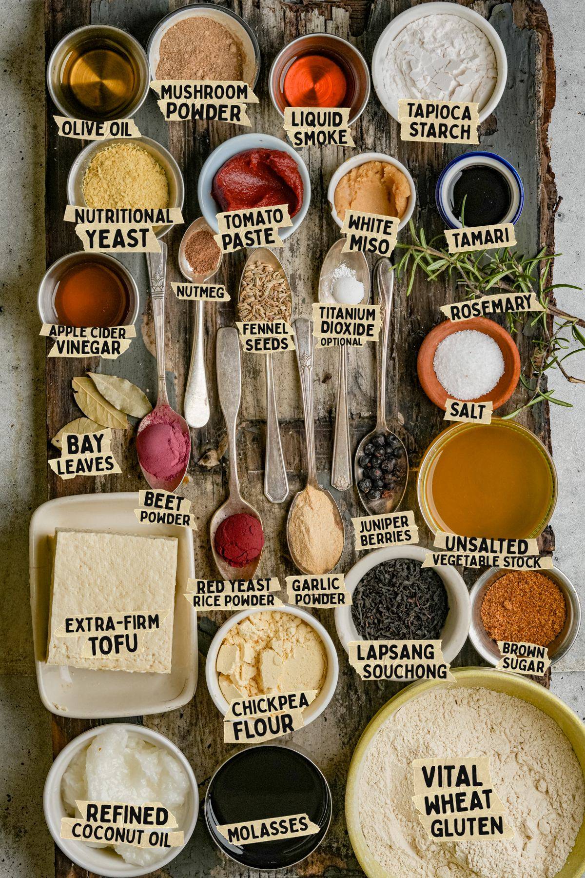 Overhead view of bowls and spoons filled with ingredients for a vegan pancetta recipe including tofu, vital wheat gluten, nutritional yeast, tomato paste, miso, and various spices.