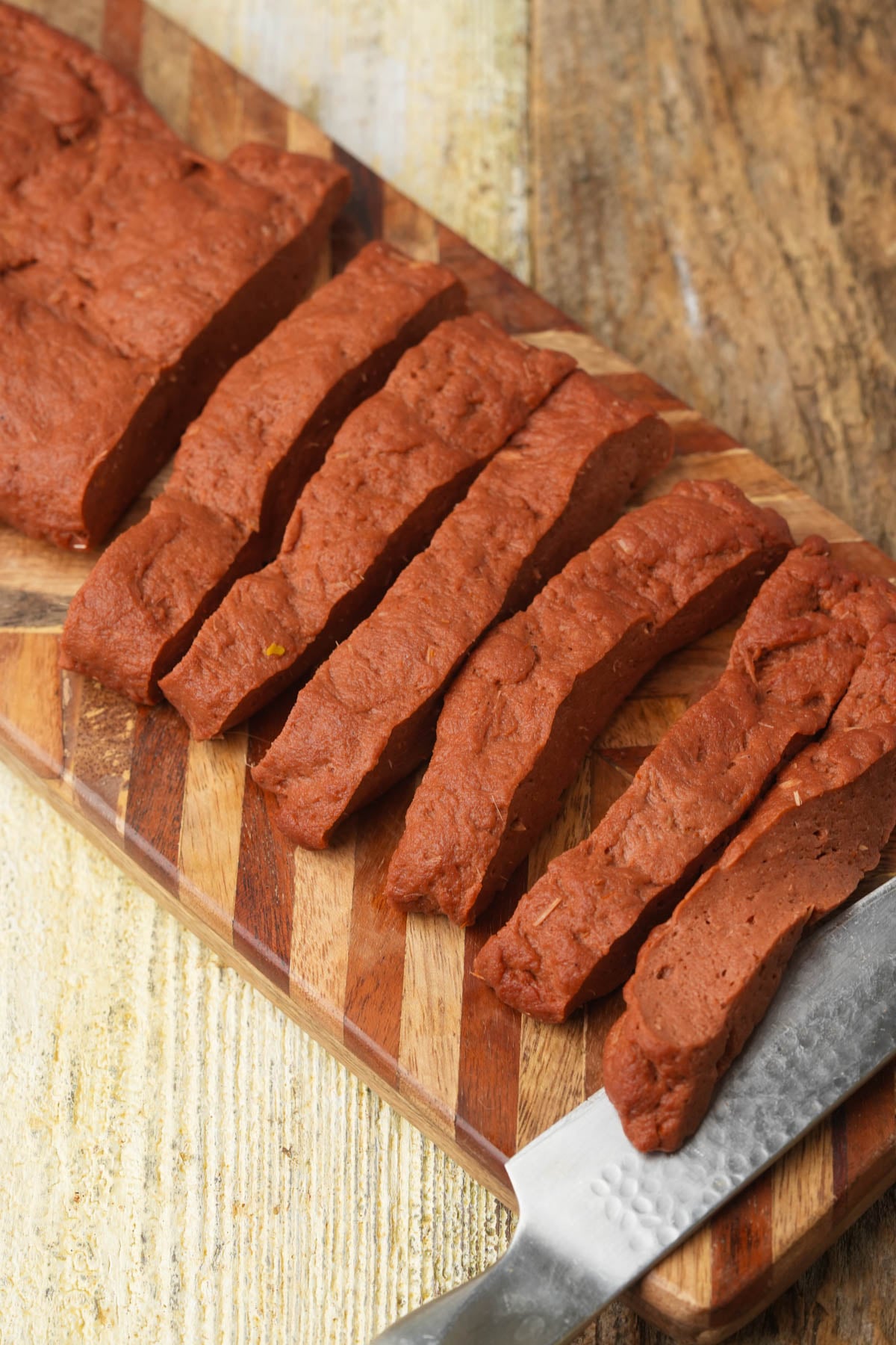 Rested seitan slab cut into rib-sized strips with a chef's knife.