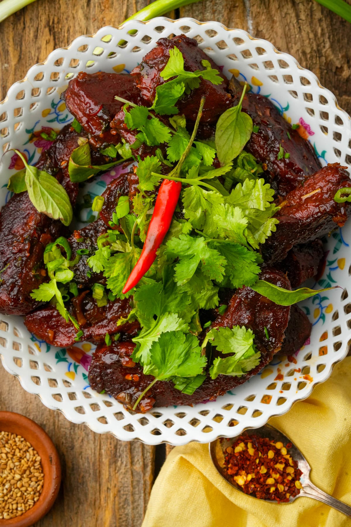 Vegan Thai seitan ribs on a platter, topped with cilantro, Thai basil and sliced bird's eye chilies.
