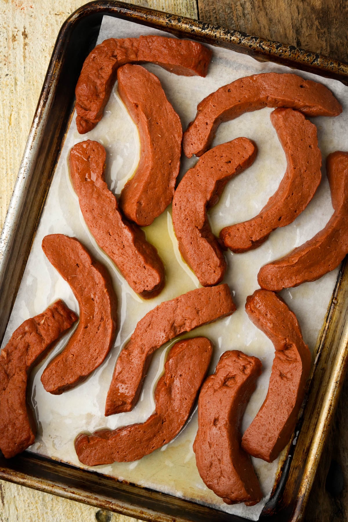 Seitan rib strips baked until firm and lightly golden on a parchment-lined pan.